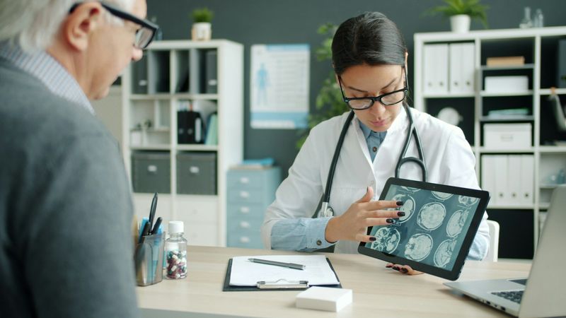 Physician reviewing brain scans on a tablet with a patient